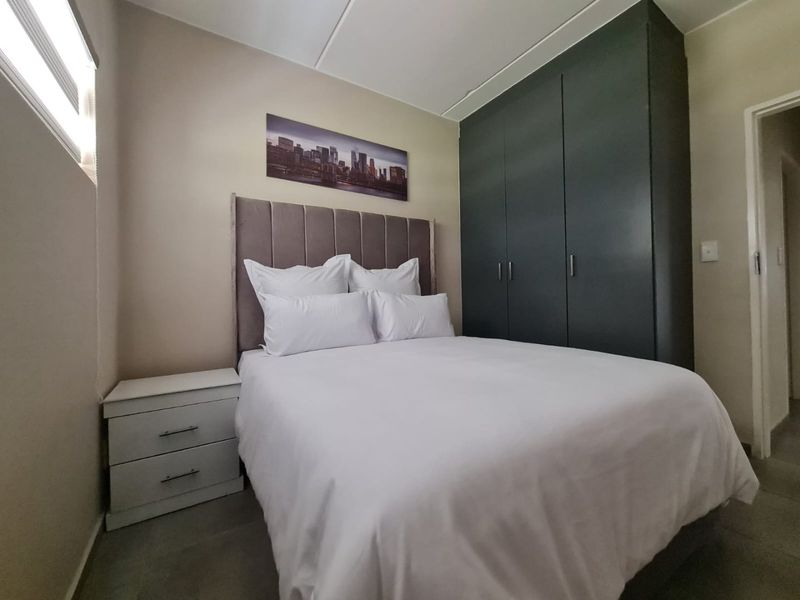 A well-maintained bedroom featuring dark built-in cupboards and neutral wall finishes, providing a clean and functional sleeping space.