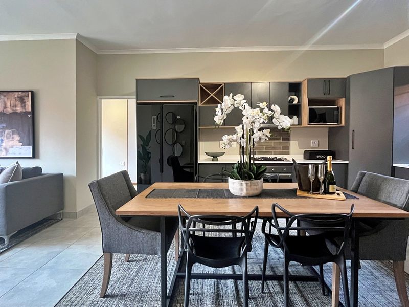Modern open-plan living and dining area featuring a contemporary kitchen with sleek cabinetry, integrated appliances, and neutral tiled flooring.