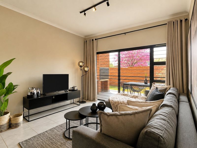 A well-maintained living room featuring modern track lighting, neutral tiled floors, and large sliding glass doors providing access to the outdoor patio area.