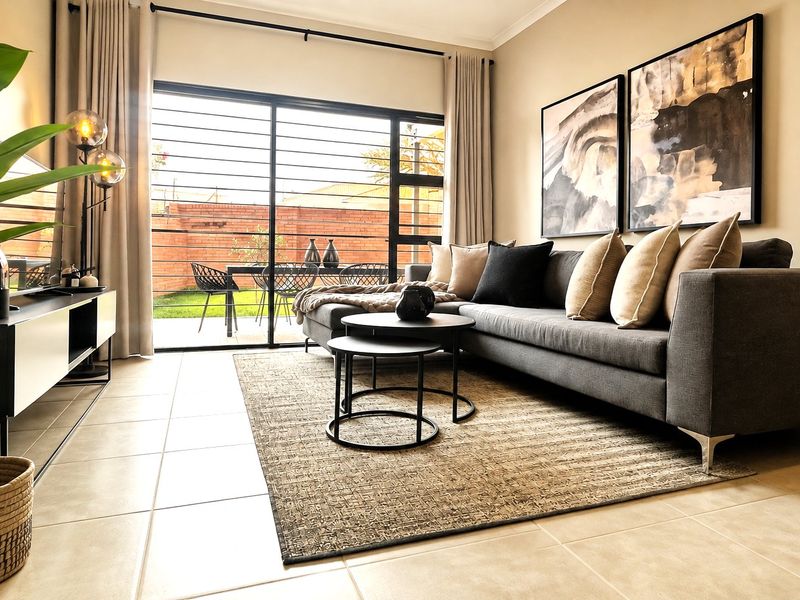 A well-lit living room featuring large sliding glass doors with security bars, providing direct access to the rear patio and garden area.