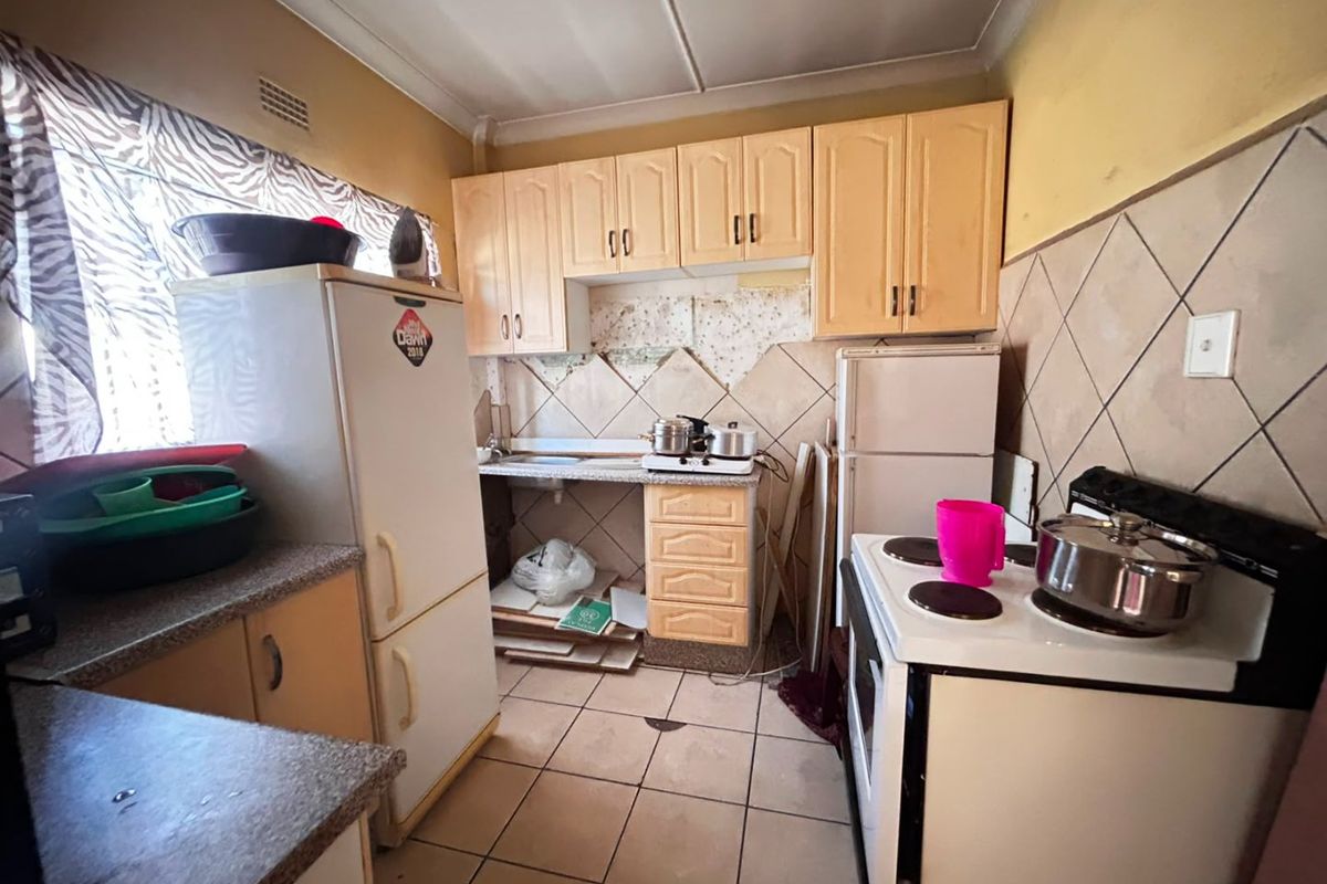 A dated kitchen featuring built-in cabinetry, tiled backsplash, and tiled flooring, currently requiring renovation and cosmetic updates to improve functionality and aesthetic appeal.