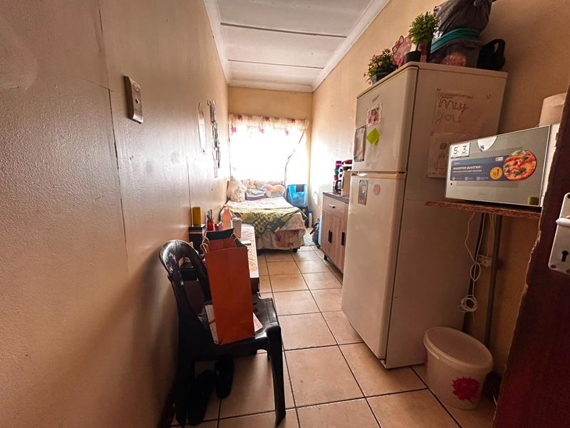 A compact open-plan living and sleeping area featuring tiled flooring and built-in cabinetry, currently showing signs of significant wear and dated finishes.