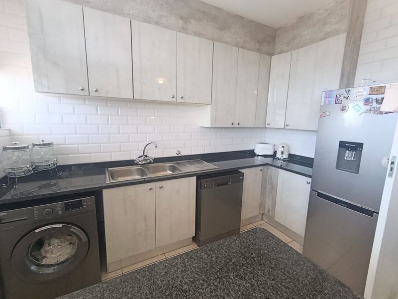 Modern kitchen featuring light-toned cabinetry, granite countertops, subway tile backsplash, and exposed concrete ceiling details, providing a functional and contemporary workspace.