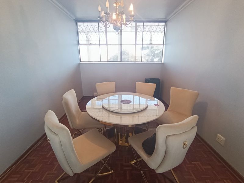 A formal dining room featuring classic parquet flooring, crown molding, and a large metal-framed window that provides natural light.