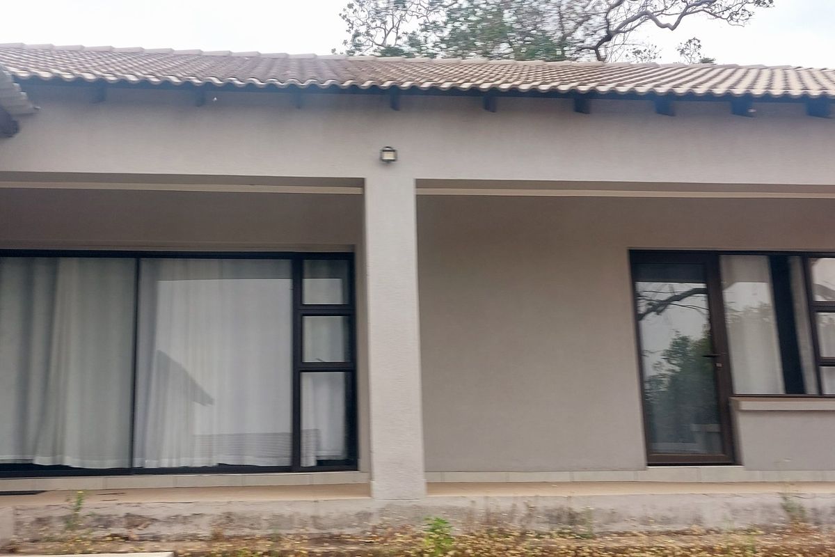 Rear exterior view of the house featuring a covered patio, sliding glass doors, and aluminium window frames under a tiled roof.