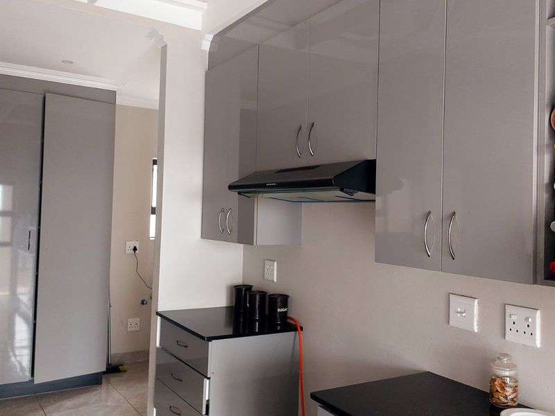 Modern kitchen featuring sleek grey cabinetry, black stone countertops, and a built-in extractor fan, offering a clean and contemporary aesthetic.