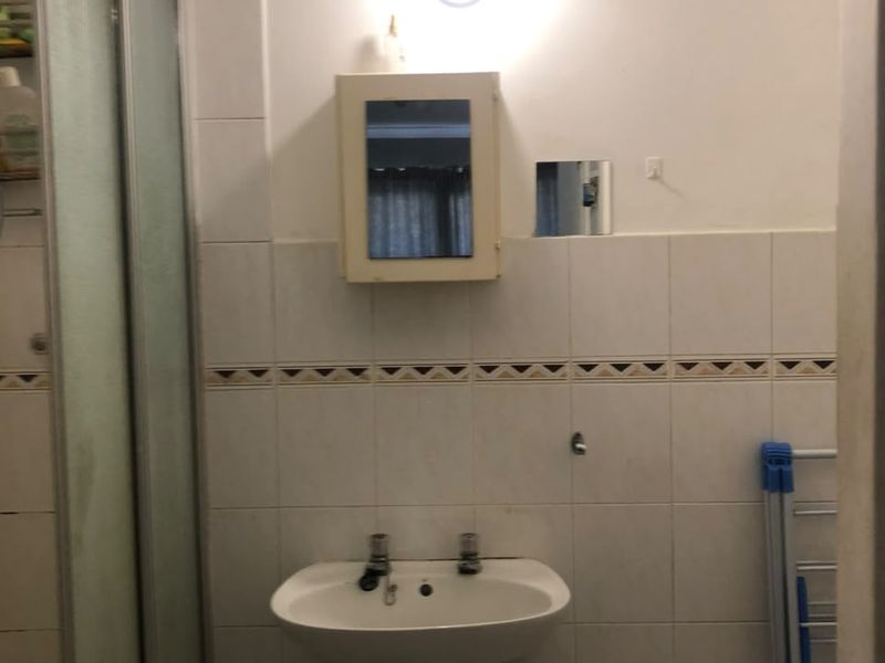 A dated bathroom featuring a pedestal sink, shower enclosure, and wall-mounted medicine cabinet with tiled walls.