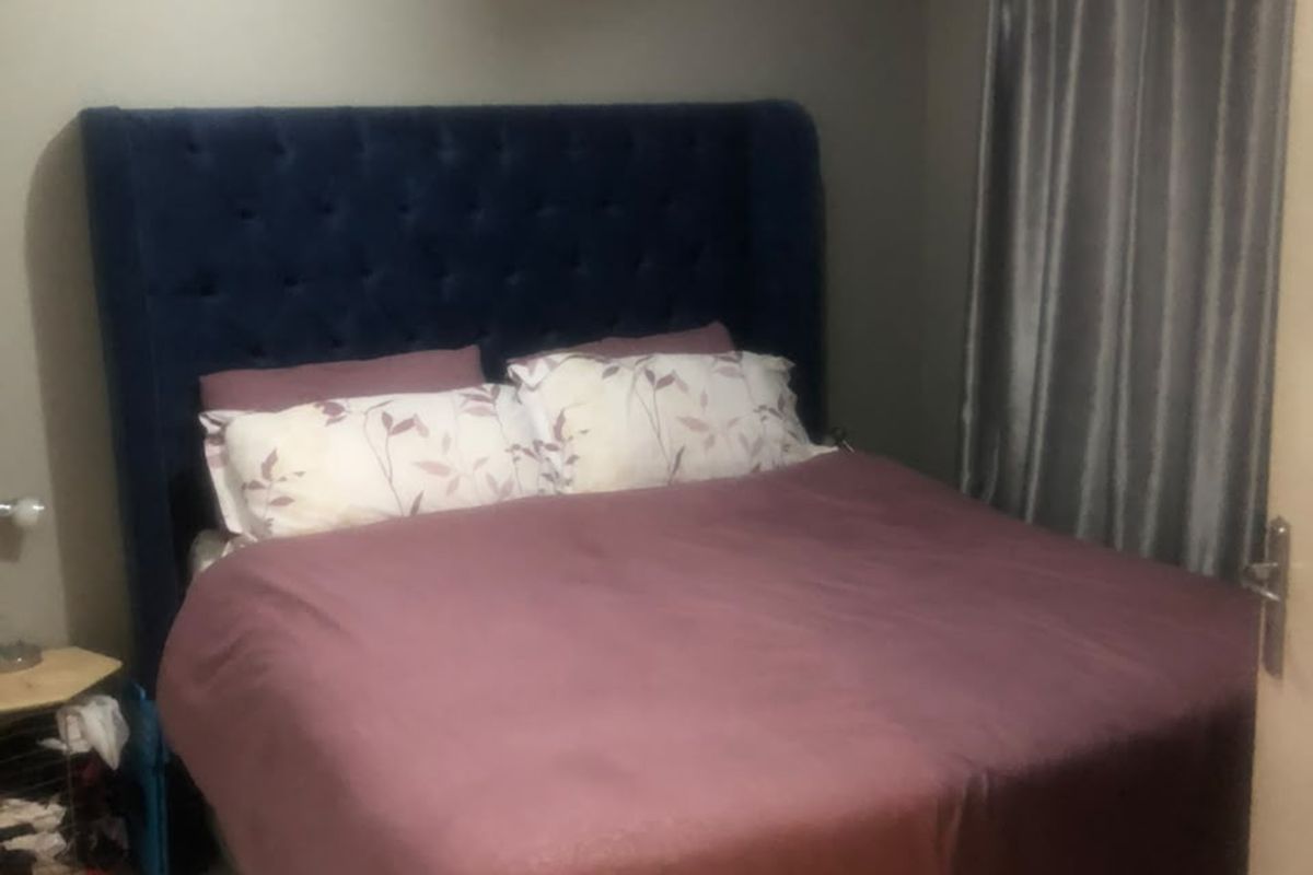 A bedroom featuring tiled flooring and neutral wall finishes, providing a functional sleeping space.