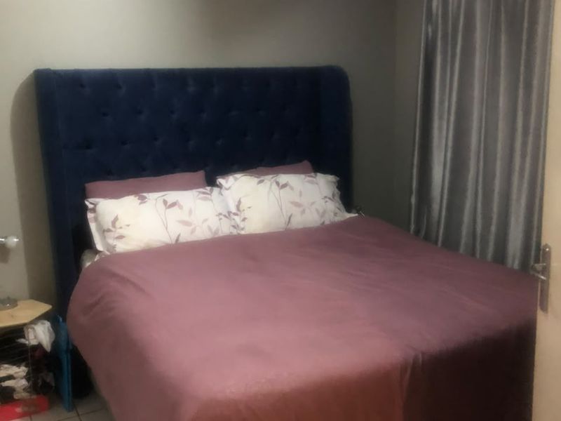 A bedroom featuring tiled flooring and neutral wall finishes, providing a functional sleeping space.