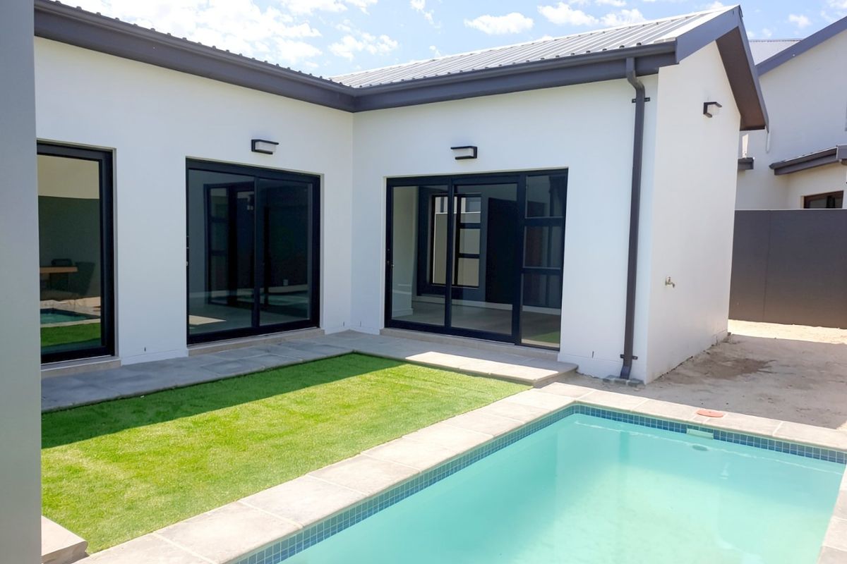 A modern rear exterior view featuring a swimming pool, manicured lawn, and large sliding glass doors providing seamless indoor-outdoor flow.