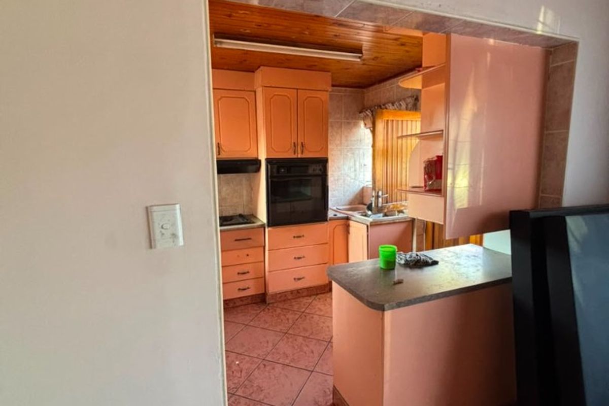 A dated kitchen featuring built-in cabinetry, an integrated oven, hob, and timber ceiling, offering potential for a modern renovation.