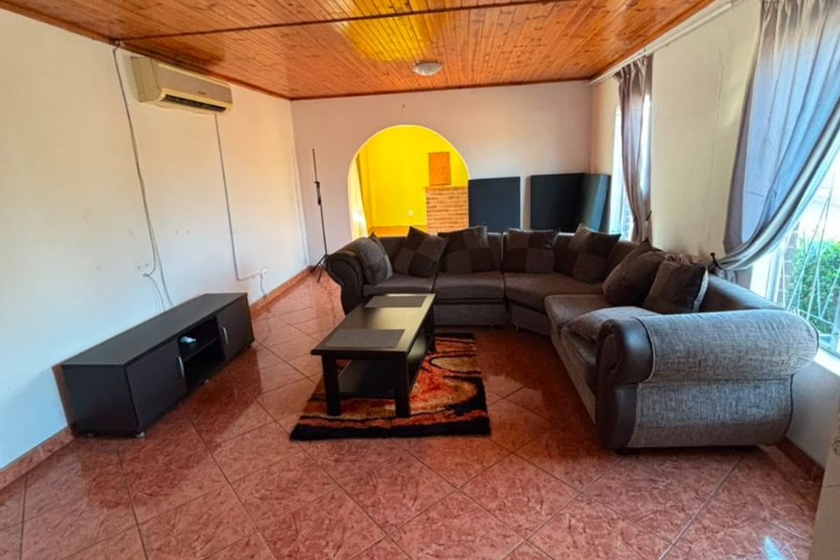Living room featuring a timber-clad ceiling, ceramic tiled flooring, and an arched entryway leading to an adjacent space.