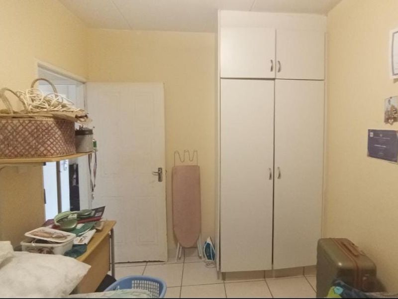 A bedroom featuring a built-in wardrobe and tiled flooring, offering a functional space with potential for cosmetic updates.