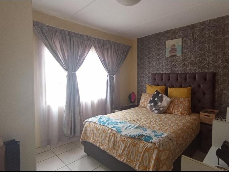 A bedroom featuring tiled flooring and a decorative patterned feature wall, providing a functional space with natural light.