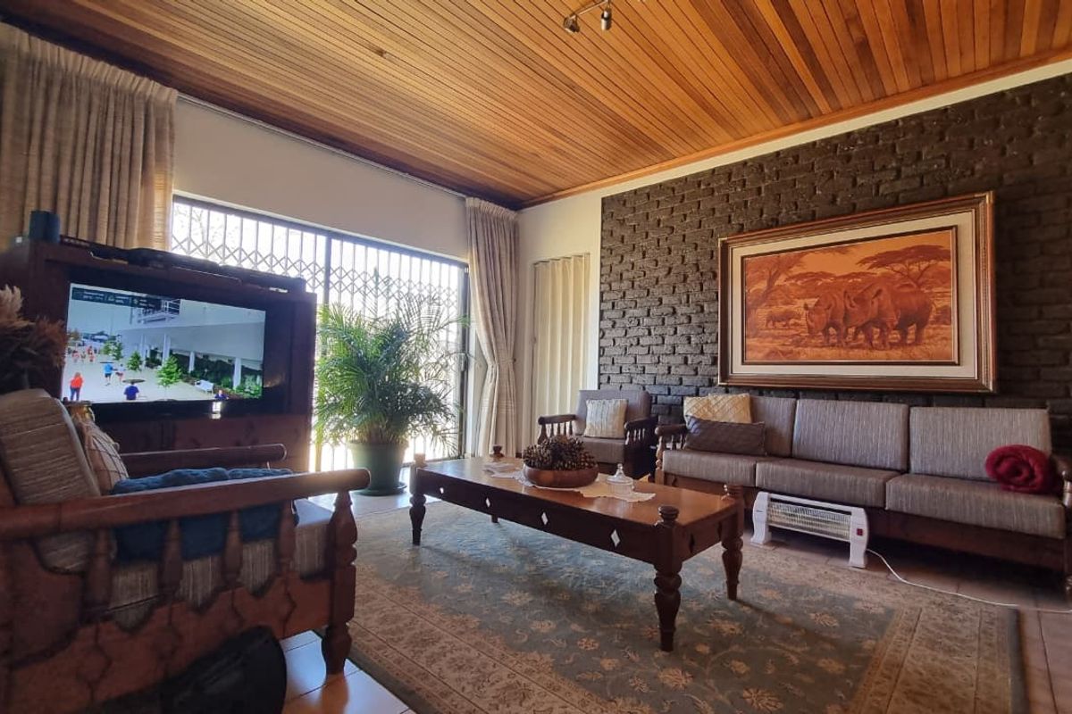 Spacious living room featuring a warm timber-clad ceiling, a textured exposed brick feature wall, and large sliding doors providing access to the outdoors.
