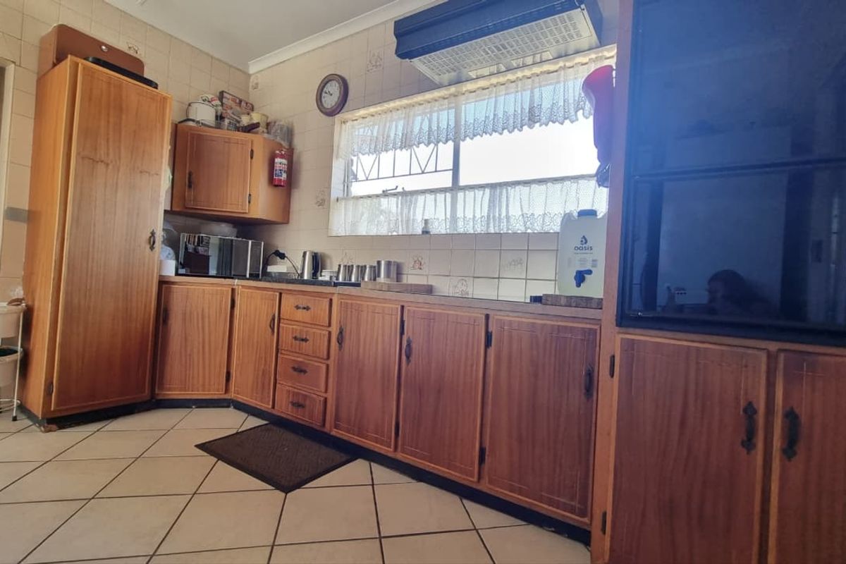 A functional kitchen featuring traditional wooden cabinetry, tiled backsplash, and tiled flooring, offering a dated aesthetic ready for modernization.