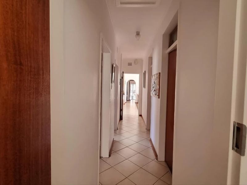 A clean, neutral hallway featuring tiled flooring and multiple internal doors providing access to various rooms throughout the home.