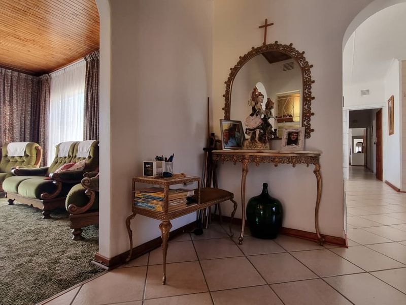 A view of the living area featuring a timber ceiling, ceramic floor tiles, and an archway leading to the hallway.
