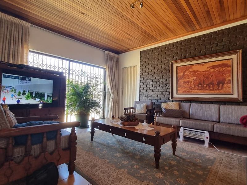 Spacious living room featuring a warm timber-clad ceiling, a textured exposed brick feature wall, and large sliding doors providing access to the outdoors.
