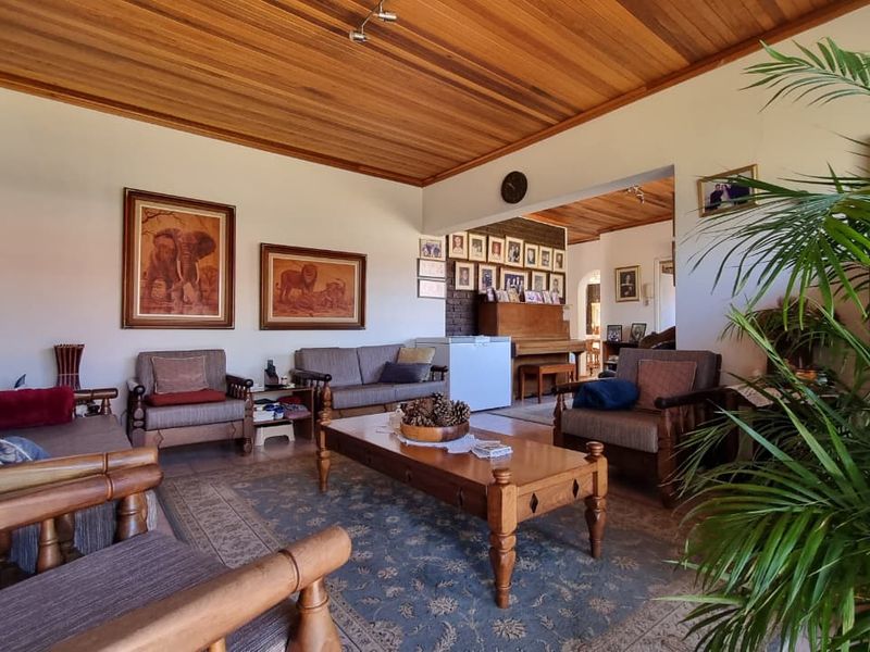 Spacious living area featuring a warm timber ceiling, exposed brick accent wall, and neutral tiled flooring, offering a comfortable and inviting atmosphere.