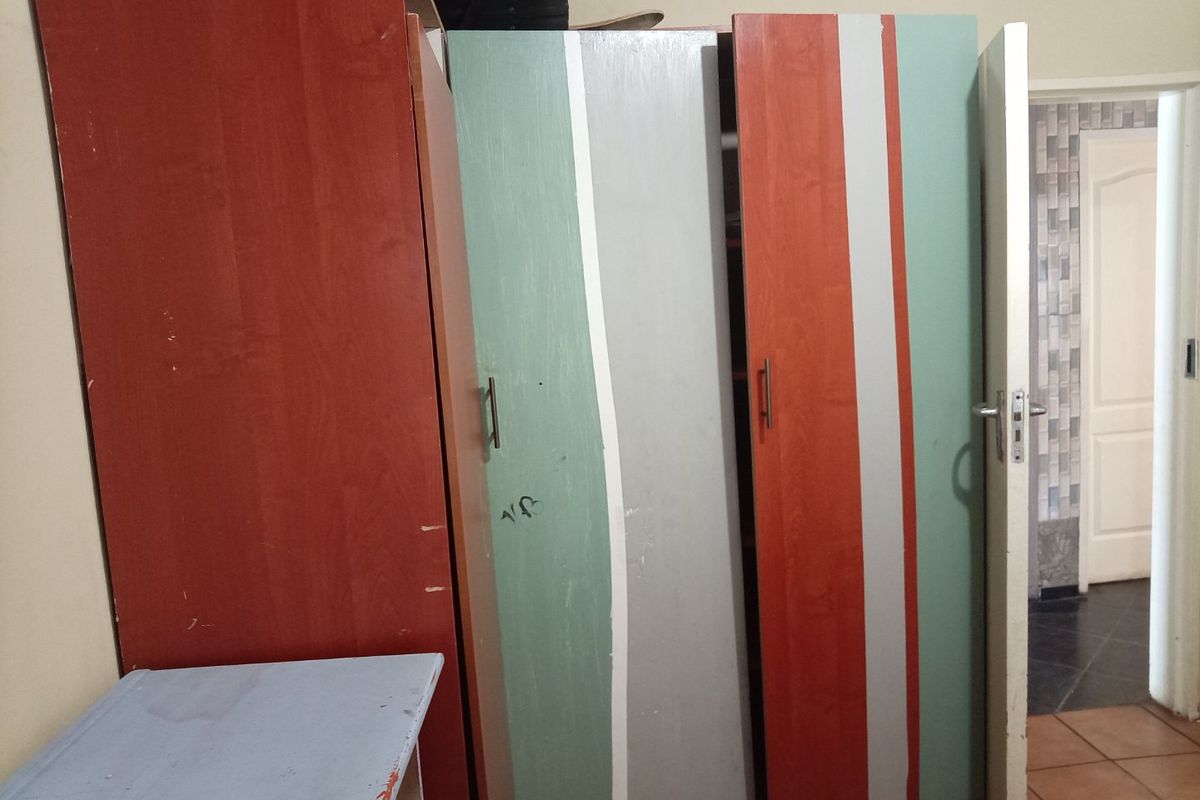 Bedroom featuring built-in cupboards with visible wear and tear on the doors, requiring cosmetic updates or replacement.