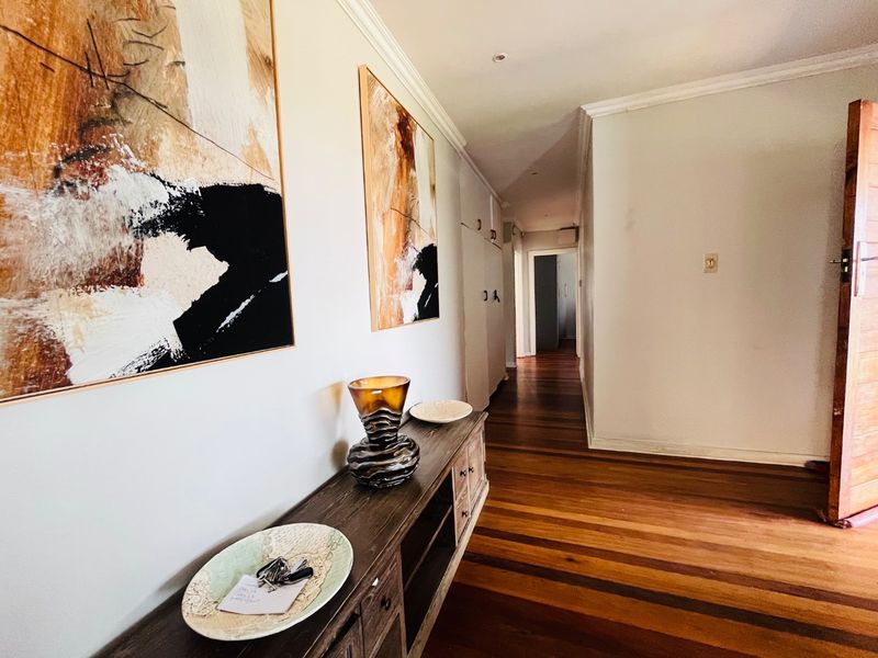A well-maintained hallway featuring polished hardwood flooring, crown molding, and built-in storage cabinetry, leading towards the interior living spaces.