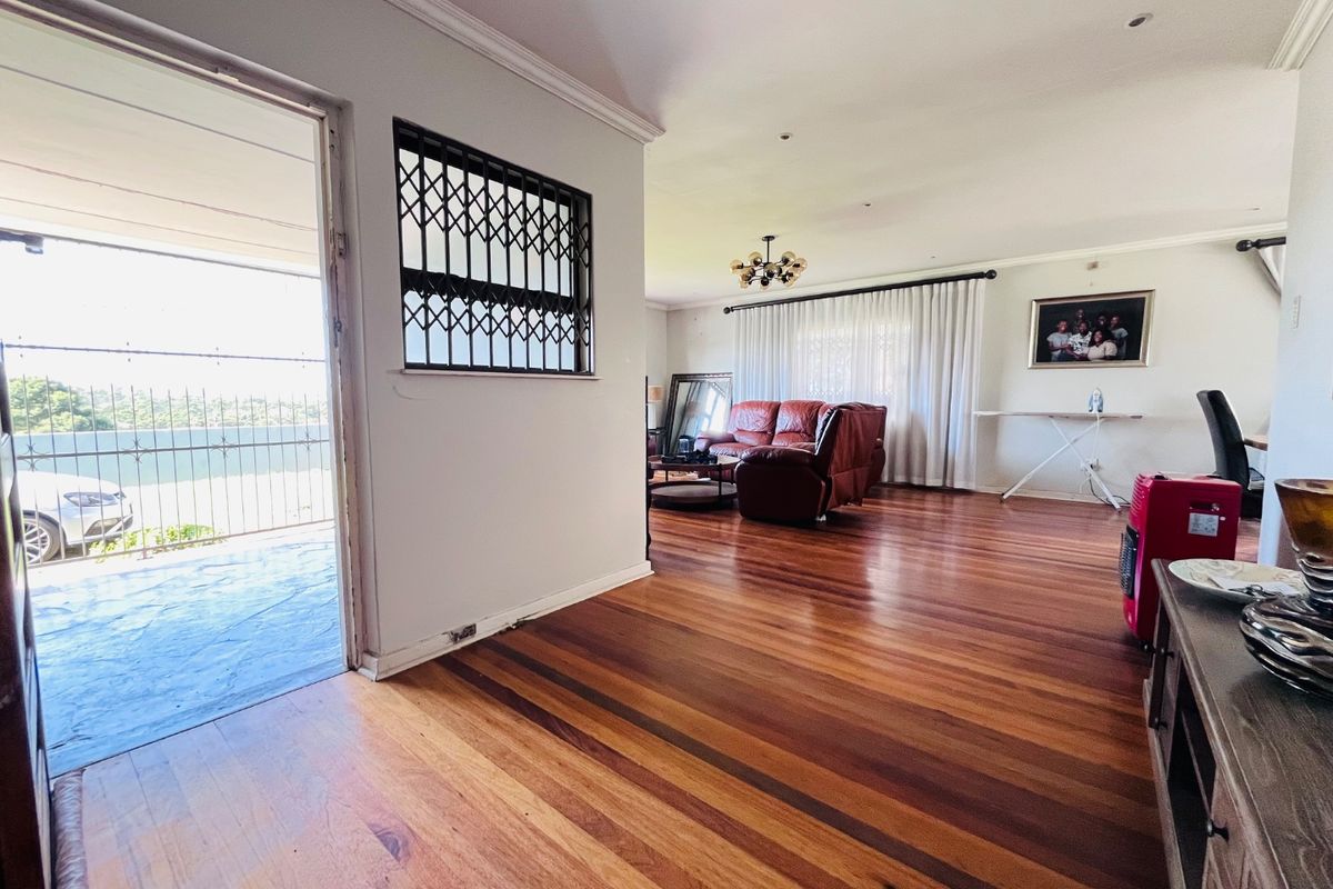 Spacious living area featuring polished hardwood flooring, crown molding, and direct access to an outdoor balcony through a sliding glass door.