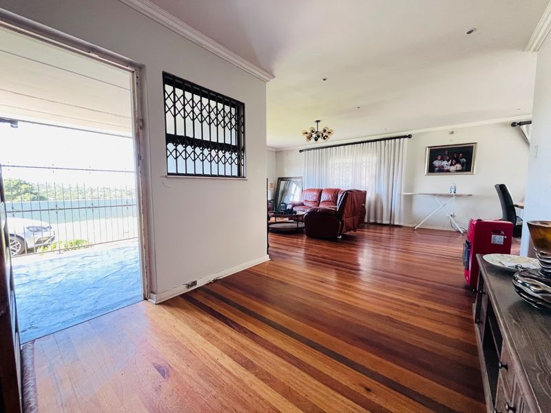 Spacious living area featuring polished hardwood flooring, crown molding, and direct access to an outdoor balcony through a sliding glass door.