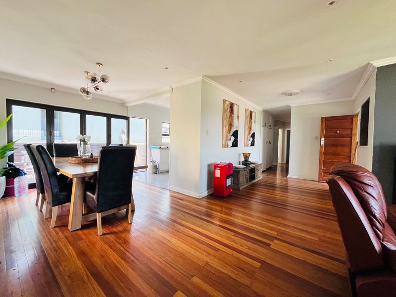 Spacious open-plan living and dining area featuring polished hardwood flooring, recessed lighting, and large sliding doors providing access to the outdoor space.