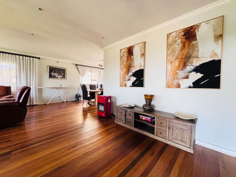 Spacious open-plan living and dining area featuring polished hardwood flooring, recessed lighting, and elegant crown molding throughout.