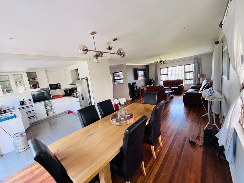 Spacious open-plan living, dining, and kitchen area featuring hardwood and tiled flooring, modern cabinetry, and integrated kitchen appliances.