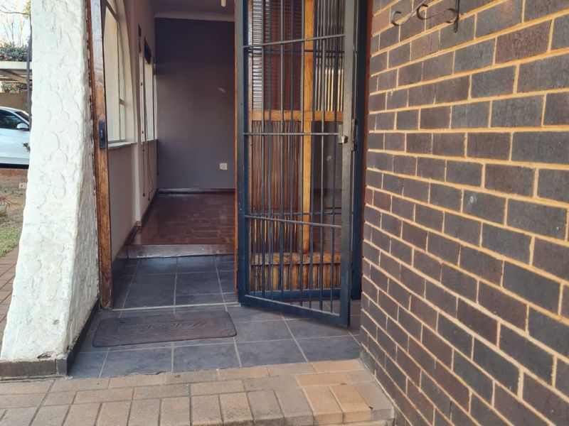 Entrance area featuring a security gate, brick facade, and tiled steps leading into the home.