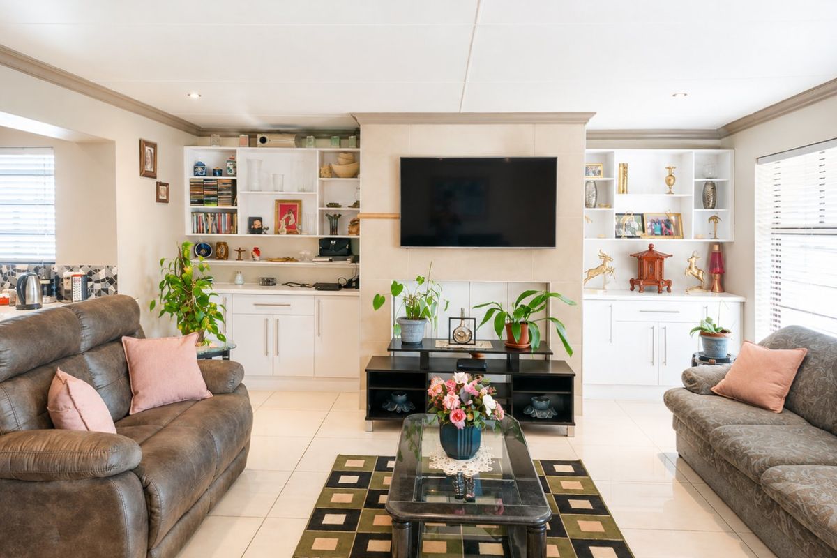 A well-maintained living room featuring built-in cabinetry, tiled flooring, and a central fireplace wall with integrated shelving.
