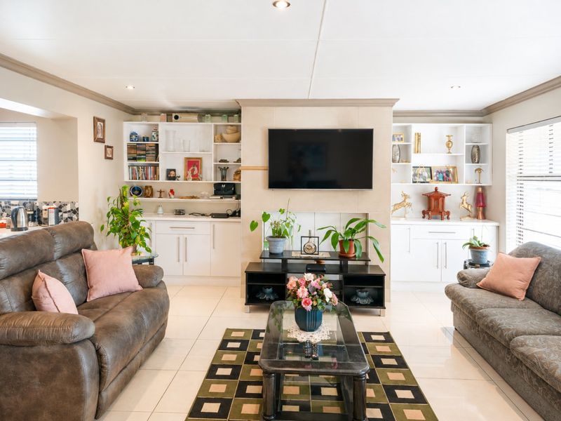 A well-maintained living room featuring built-in cabinetry, tiled flooring, and a central fireplace wall with integrated shelving.