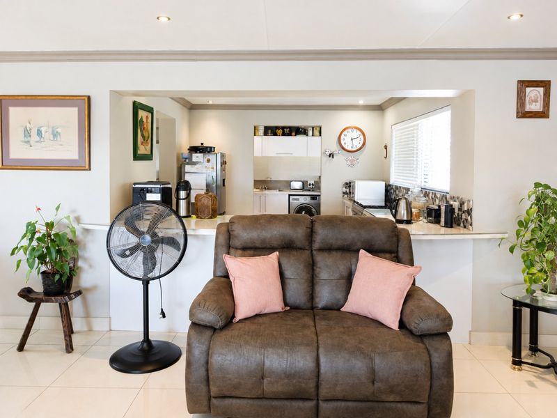 An open-plan living area featuring a kitchen with built-in cabinetry and a breakfast bar, seamlessly connected to the main living space.