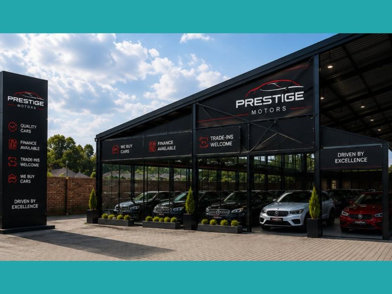 Modern commercial vehicle showroom featuring a steel and glass structure, paved frontage, and prominent branding signage.
