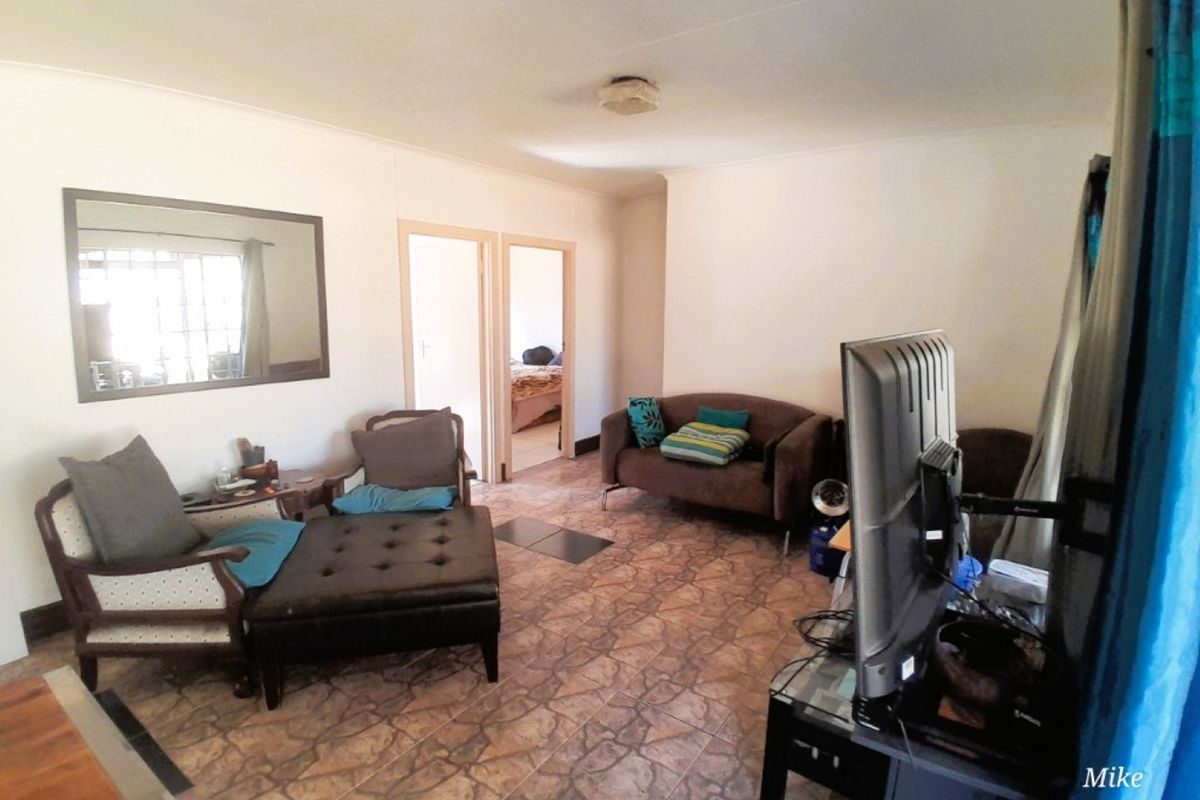 A living room area featuring tiled flooring and access to adjacent rooms, requiring cosmetic updates to improve the overall aesthetic.