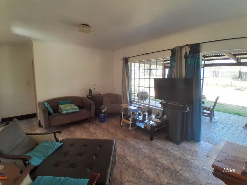 A living room featuring tiled flooring, large windows, and direct access to an outdoor patio area.