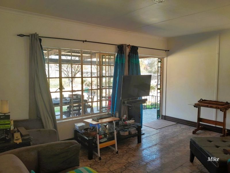 A living room featuring tiled flooring, large windows, and direct access to an outdoor patio area.