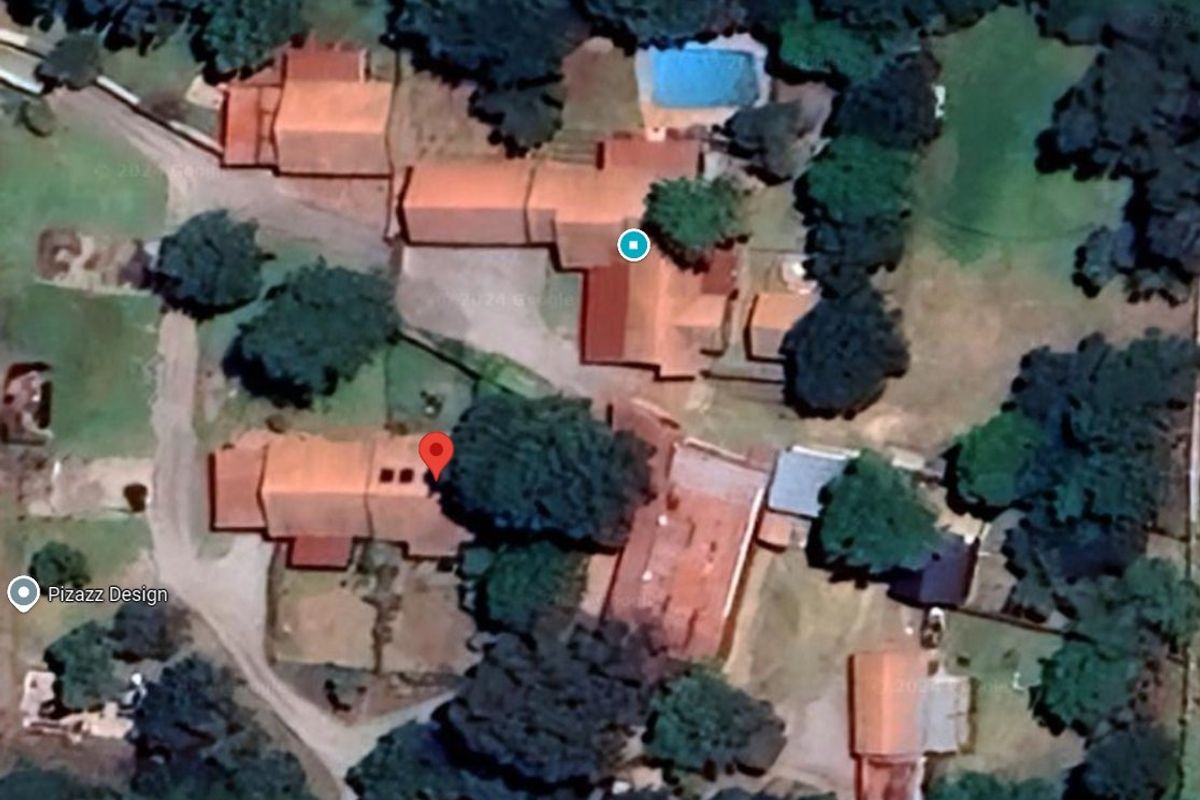 Aerial satellite view of the property complex showing multiple buildings, tiled roofs, and a swimming pool set within a landscaped garden area.