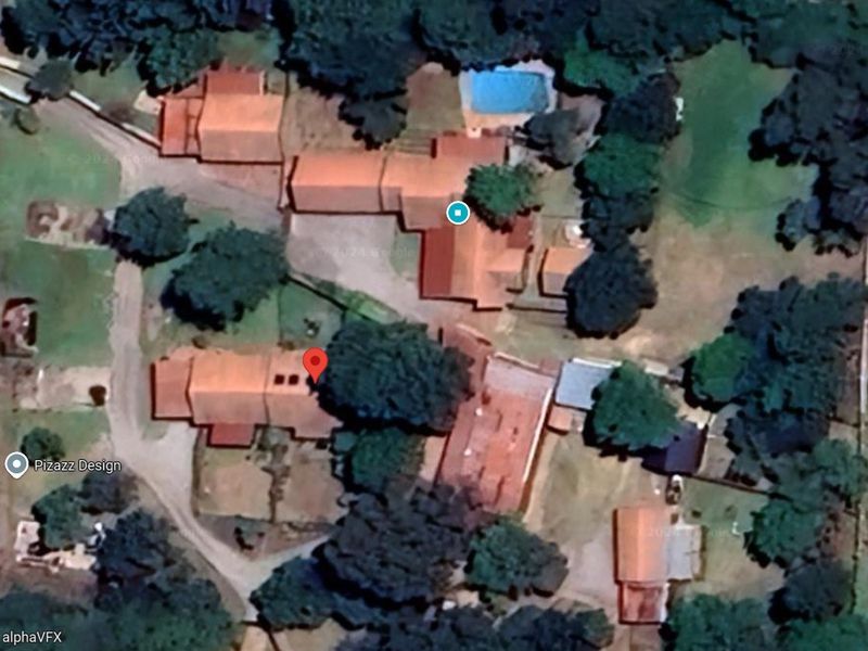 Aerial satellite view of the property complex showing multiple buildings, tiled roofs, and a swimming pool set within a landscaped garden area.