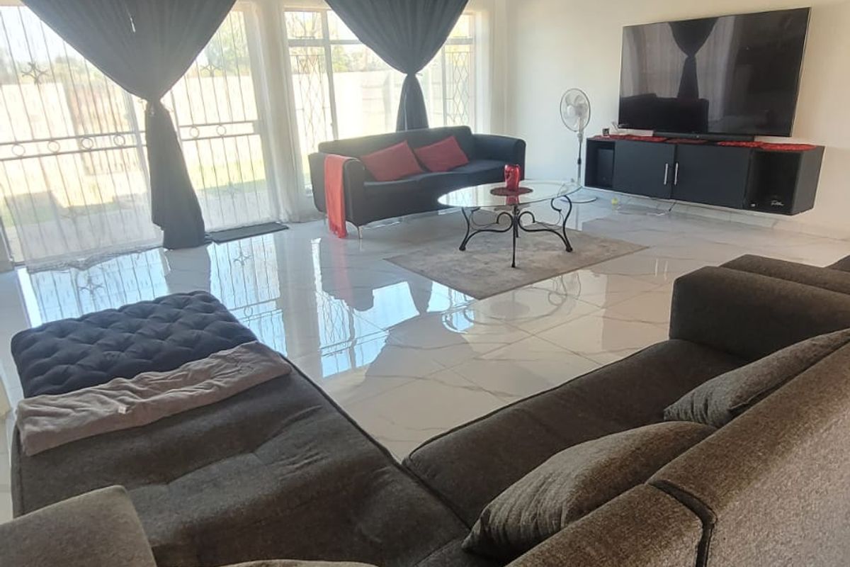 Spacious living area featuring polished porcelain tile flooring, a dark timber-clad ceiling, and large sliding glass doors with integrated security gates.
