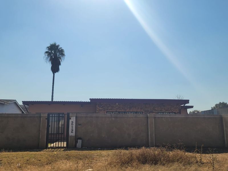 Front exterior view of the commercial property featuring a perimeter wall, metal gate, and brick facade under a flat roof structure.