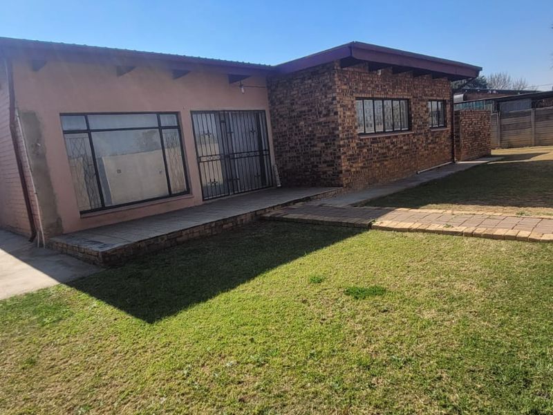 Rear view of the commercial property featuring a combination of brick and plastered exterior walls, paved walkways, and a lawn area.