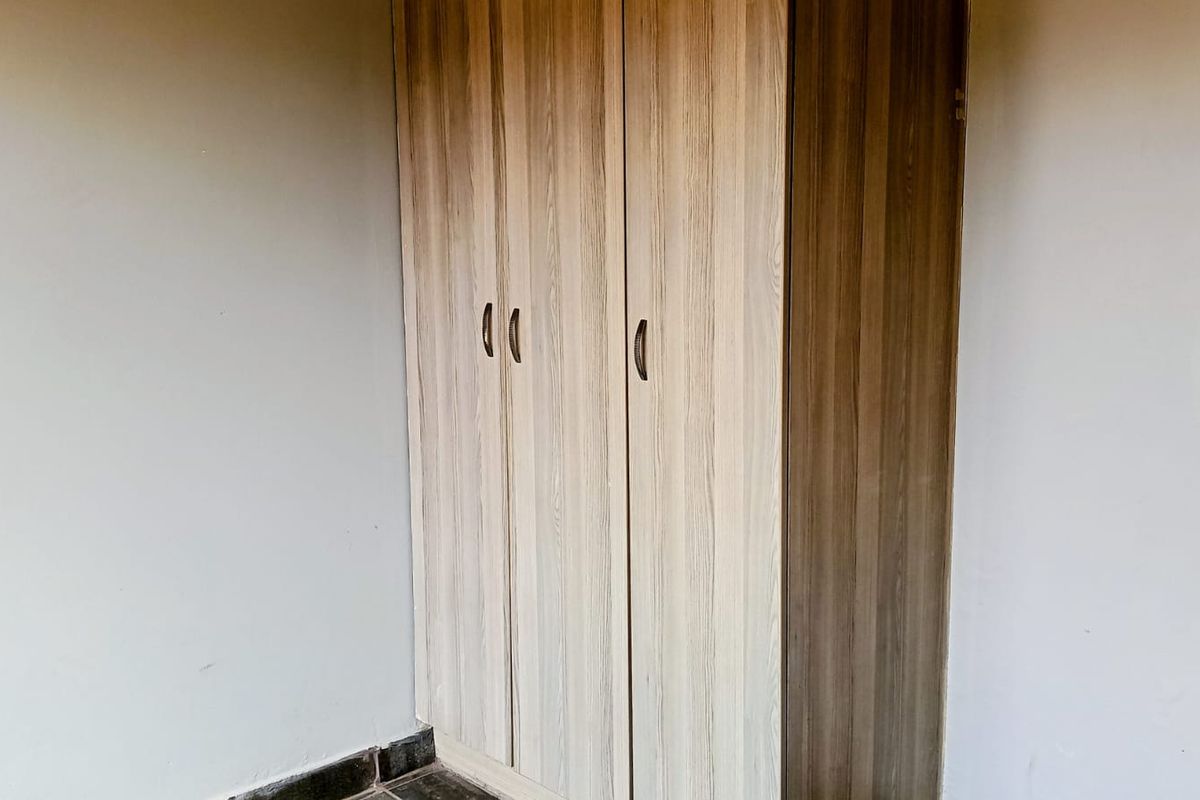 A bedroom featuring a modern built-in wardrobe with wood-grain finish cabinetry.