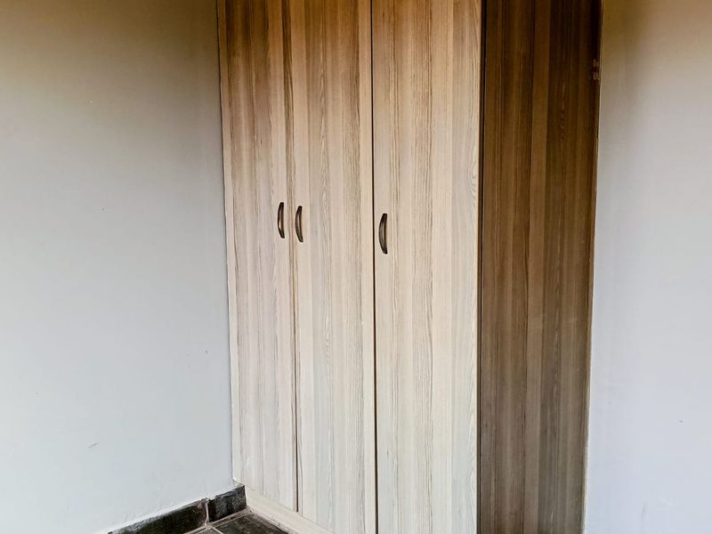 A bedroom featuring a modern built-in wardrobe with wood-grain finish cabinetry.