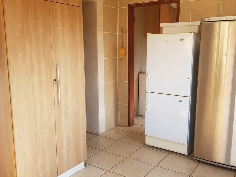 A functional scullery or utility area featuring tiled walls, tiled flooring, and built-in wooden cabinetry providing ample storage space.