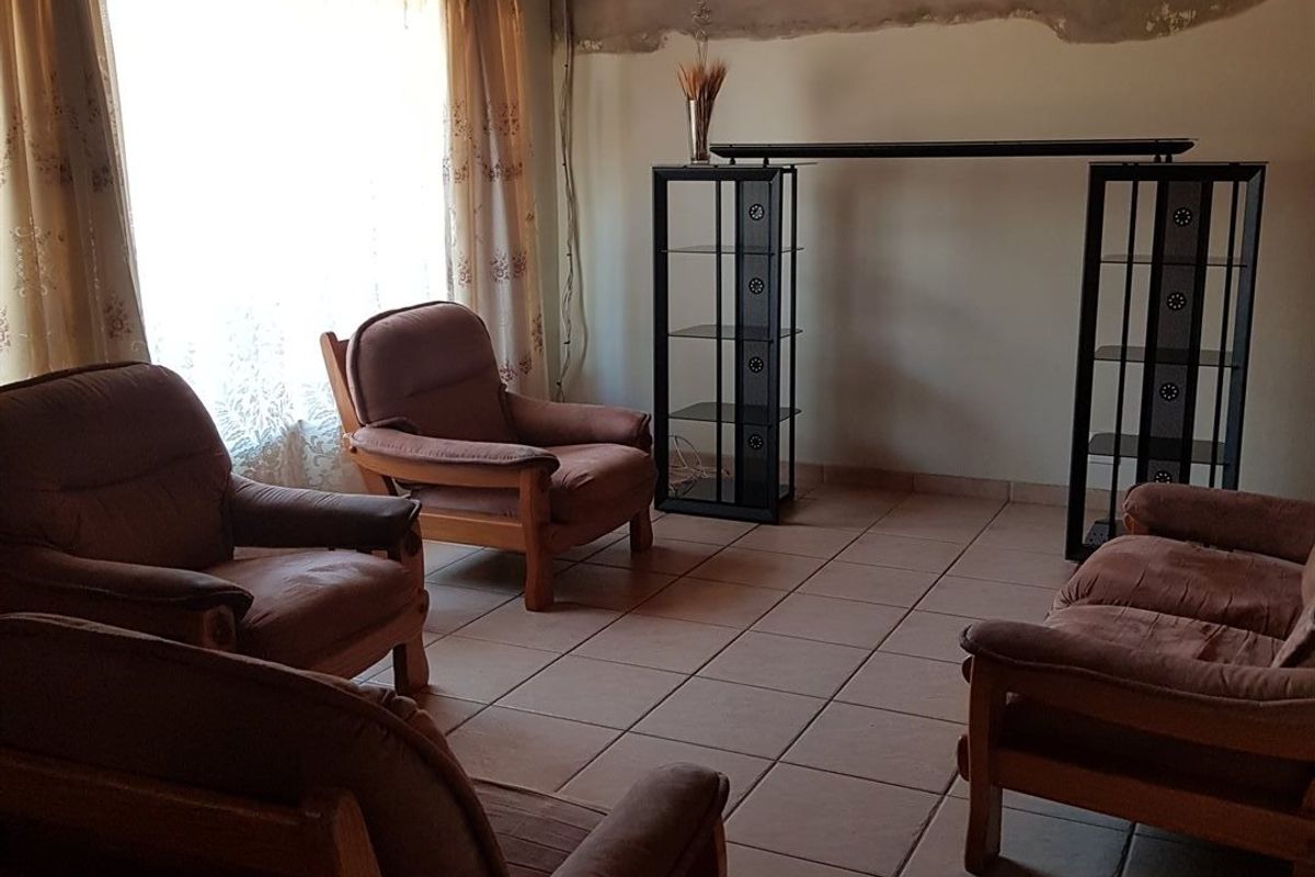 Living room featuring tiled flooring, a timber ceiling, and a wall-mounted air conditioning unit, with unfinished wall plastering requiring cosmetic attention.