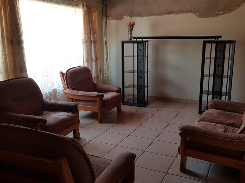 Living room featuring tiled flooring, a timber ceiling, and a wall-mounted air conditioning unit, with unfinished wall plastering requiring cosmetic attention.