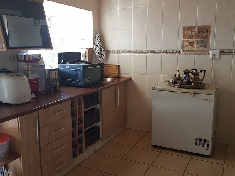 A functional kitchen featuring laminate cabinetry, tiled splashbacks, tiled flooring, and a timber-clad ceiling, offering a practical workspace with integrated storage.